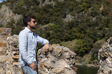 Man traveling to towns doing tourism. Man walking and enjoying the views. Young man walking through nature and enjoying the tranquility and fresh air with his sunglasses.