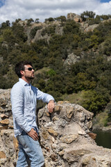 Fototapeta premium Man traveling to towns doing tourism. Man walking and enjoying the views. Young man walking through nature and enjoying the tranquility and fresh air with his sunglasses.