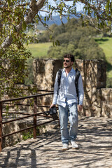 man walking through nature with his video camera. Man recording in nature with his video camera. Professional doing a video report in nature. Boy doing nature tourism, traveling with his camera.