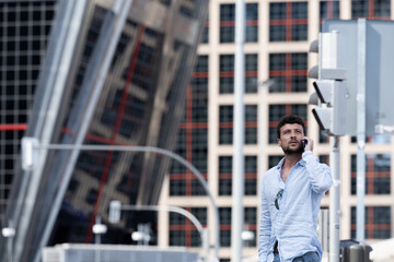 Man walking on the street talking on mobile phone. Businessman talking to his team while he passes through a pedestrian crossing. Man crossing the street while he has a conversation on his cell phone.