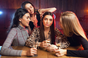 Friends are trying to cheer up a sad girl. Girls drink at a bar.