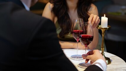 Happy romantic couple sitting in the restaurant, having date and holding glasses with red wine....