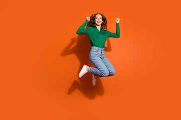 Full length photo of cheerful lucky lady dressed green shirt jumping high rising fists isolated...