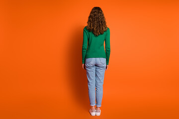Full length photo of slender slim lady dressed green shirt standing back isolated orange color...