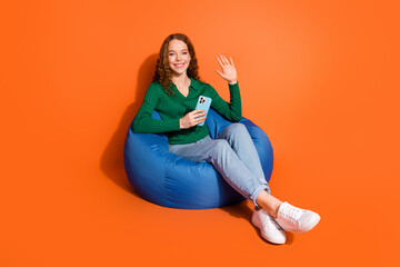 Full length photo of friendly cute lady dressed green shirt waving arm hi texting modern device...