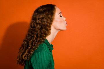 Photo of dreamy adorable lady dressed green shirt blowing kiss emtpy space isolated orange color...