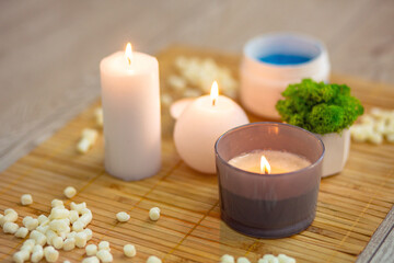 Closeup of a bright modern massage room interior details, burning candles and blue massage salt standing on a bamboo mat
