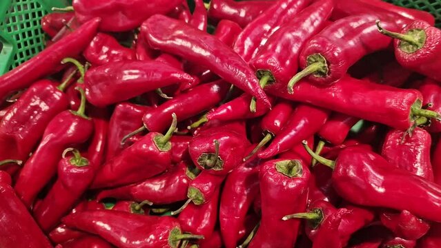 Red pepper in a plastic green box on a market or store counter. Capi red pepper close-up in a supermarket. Selling vegetables