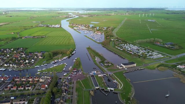 Aerial drone view of lock complex in Frisian city of Stavoren. Large pumping station beside bridge and sluice and historic town with canal, lake, and waterways	