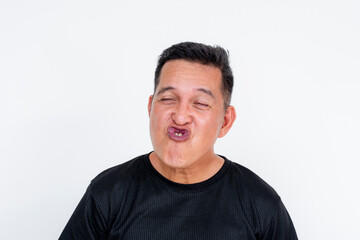 Fototapeta premium A funny expressive portrait of an Asian man isolated on a white background, puckering lips and squinting eyes.
