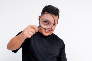 A middle-aged Asian man smiling as he peers through a magnifying glass, showing great interest, isolated on a white background.