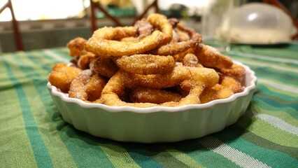 A tray of fried dough snakes with sugar ready to eat. Traditional Italian Frittelle.