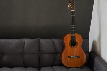 Creole guitar standing on top of a gray armchair. Window light and copy space