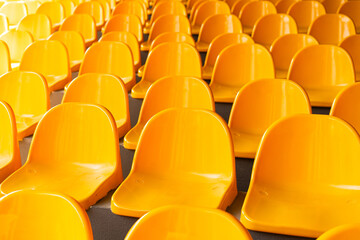Plenty of yellow plastic seats at stadium. Bright yellow seats for fans at a football stadium in summer