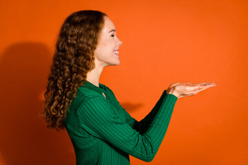 Photo of excited positive lady dressed green shirt holding arms emtpy space isolated orange color...