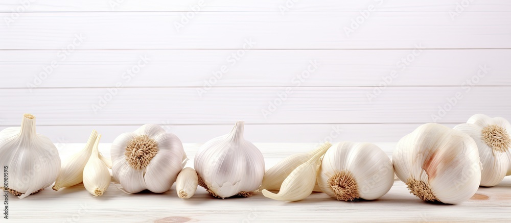 Poster a copy space image of organic garlic fresh and aromatic placed on a clean white wooden table with ro