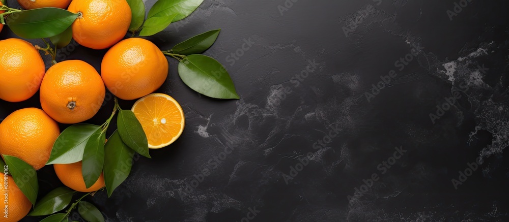 Poster top view of a flat lay fruit composition featuring an orange or tangerine with leaves placed on a bl