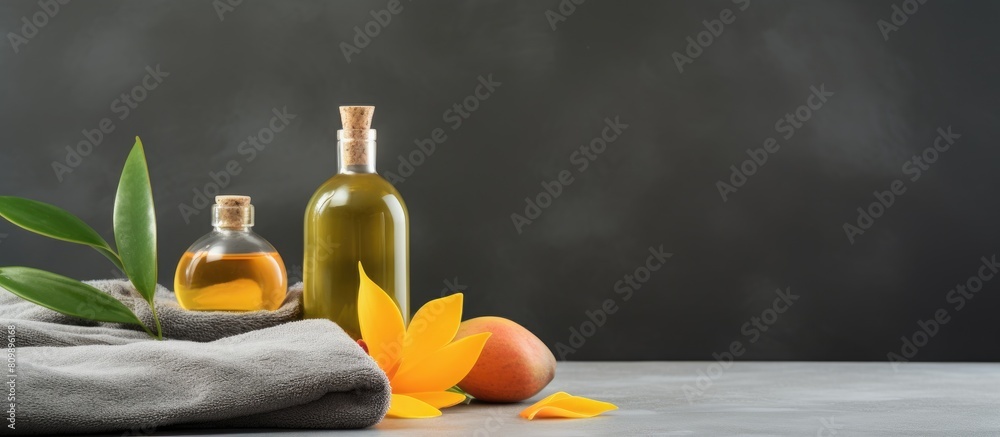 Poster On a grey background there is an arrangement of mango essential oil and bath supplies creating a visually appealing copy space image