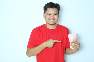 Asian man showing smiling expression while holding paper money and right hand to pointing at it