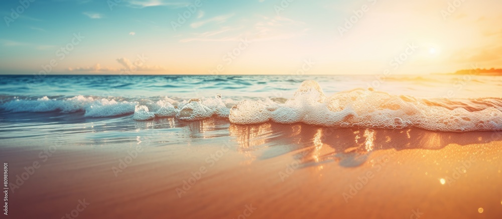 Poster blurry tropical sunset beach with the bokeh effect of sunlight on the waves creates an abstract back
