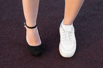 Girl's legs in casual and sports shoes. Choice of shoe type. Comfortable sneakers and high heels. Close-up shot