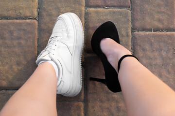 Girl's legs in casual and sports shoes. Choice of shoe type. Comfortable sneakers and high heels. Close-up shot. View from above