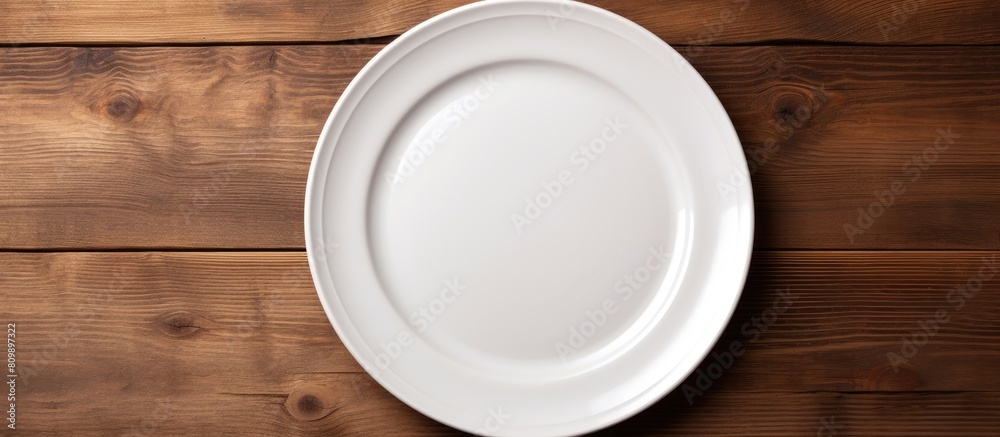 Poster copy space image of a white plate resting on a striped napkin on the backdrop of an aged wooden tabl