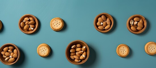 Fototapeta premium An overhead view of circular hazelnut cookies placed beside a blue backdrop offering plenty of space for additional content