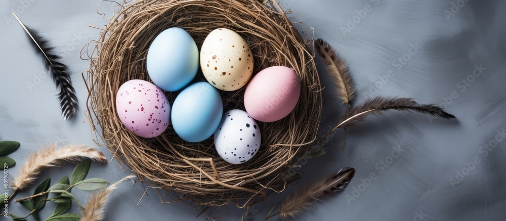 Poster A trendy minimalist Easter themed flatlay with a top down perspective The image showcases colorful eggs and a nest portraying the essence of the spring season Ample copy space is available for adding