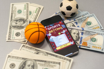 Smartphone with gambling mobile application and basketball ball with money close-up. Sport and...