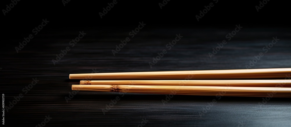 Poster a copy space image of wooden chopsticks placed on a black table surface
