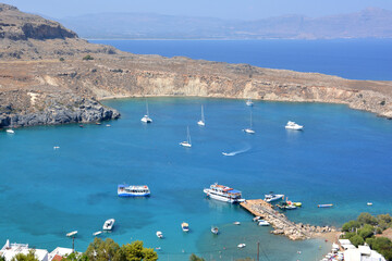 a marina with many boats and a blue water with a mountain in the background  