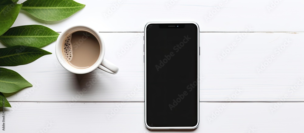 Fototapete a phone mockup rests on a white table accompanied by a cup of coffee and leaves creating a visually 