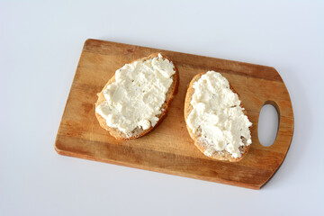 a wooden cutting board with slices of bread and cottage cheese