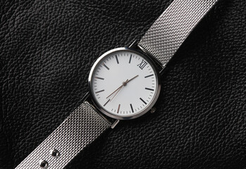 Women's analog silver wristwatch on a black leather surface