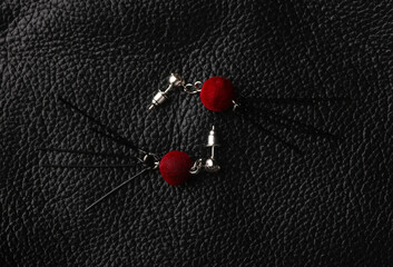 Stylish stud earrings on black leather background