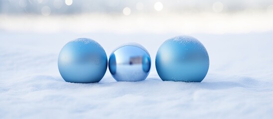 Three blue ornaments placed on the snowy ground forming an attractive composition with ample copy space image