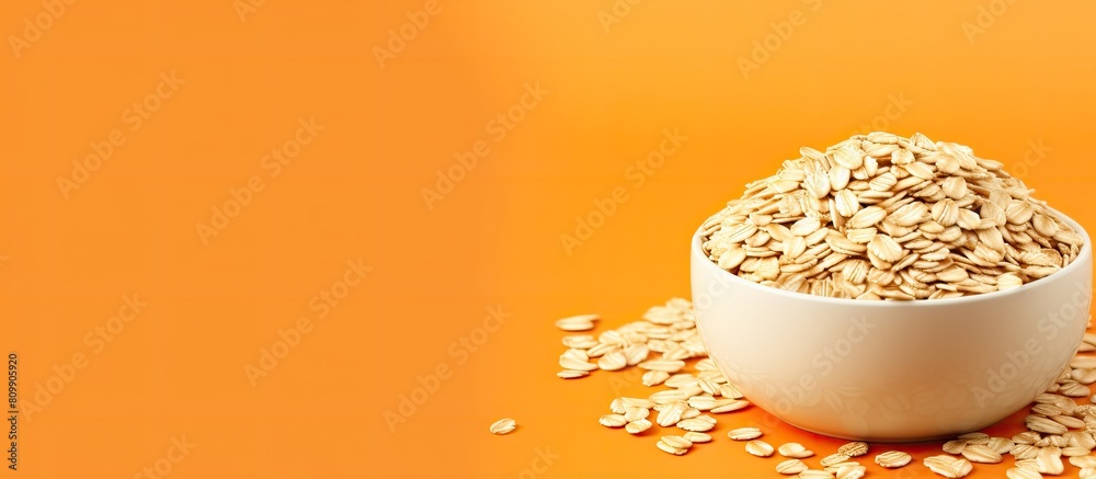 Poster copy space image of a bowl filled with uncooked oatmeal flakes placed on a vibrant orange background
