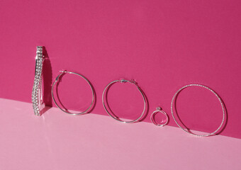 Silver jewelry accessories on pink background. Earrings, hairpin, and ring. Creative layout. Beauty...