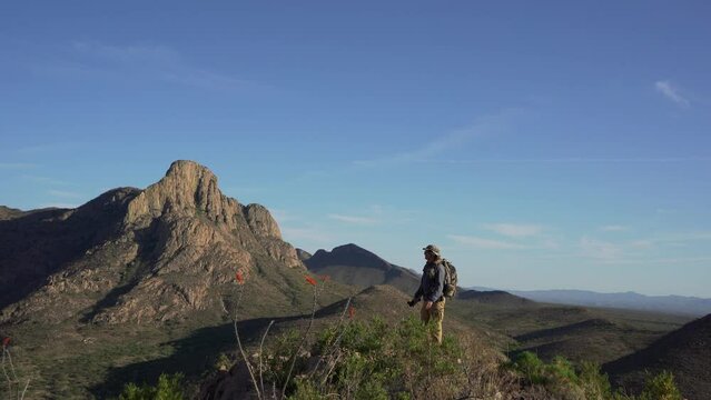 A man hikes to the summit of a desert mountain