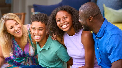 Portrait Of Family With Teenage Children Laughing And Smiling Sitting Outdoors At Home On Deck