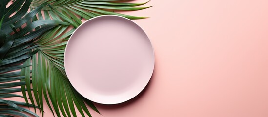 A minimalistic top down view of millennial pink paper background with an empty plate placeholder surrounded by vibrant green tropical palm leaves Perfect for your text or design ideas A visually appe