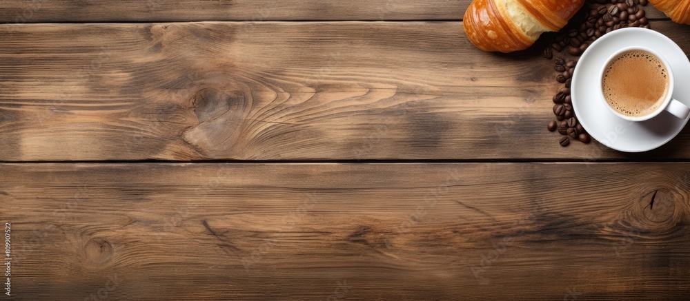 Poster A top down view of a wooden table adorned with fresh croissants and a cup of coffee with ample space for additional elements