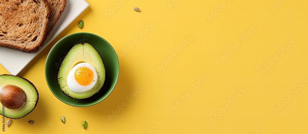 Poster A healthy breakfast featuring avocado egg and toast is presented on a yellow background The top down view allows for a copy space image