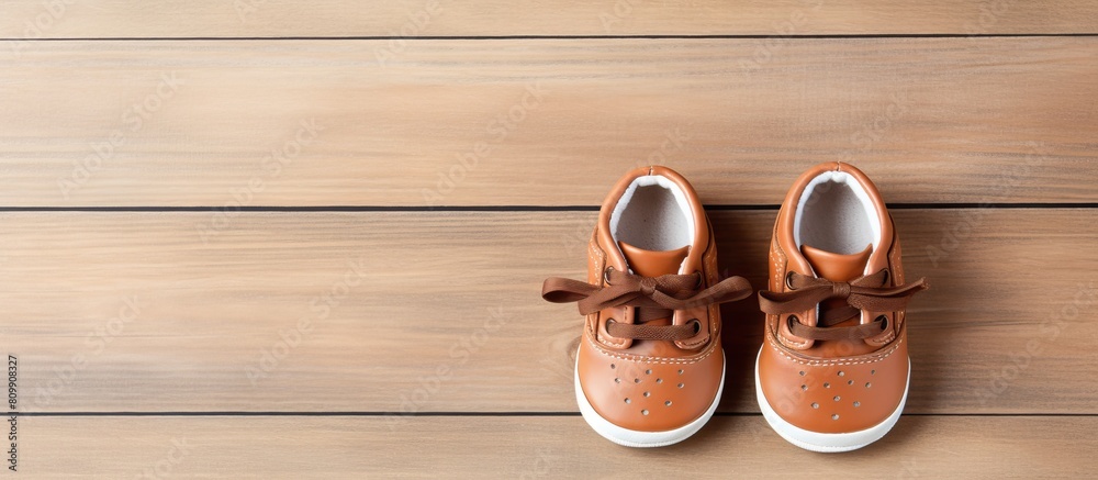 Poster Top view of adorable baby shoes placed on a wooden background creating a charming composition with copy space for an image