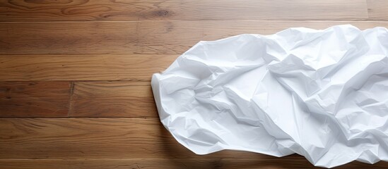 Obraz premium A crumpled white sheet of paper is seen in a lumpy state on a wooden floor creating a copy space image