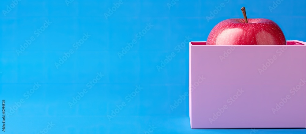 Poster a stunning pink apple is inside a box placed on a blue background leaving space for an image. creati