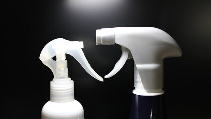 Two plastic bottles with sprayer opposite each other isolated on black 