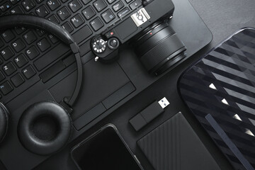 Modern black gadgets and accessories. Laptop, camera, smartphone, stereo headphones, usb flash...