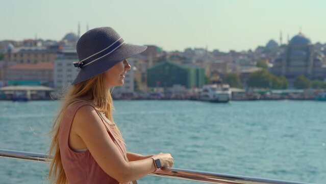 A young woman tourist wearing a hat is abloom with joy as she cruises the Bosphorus Strait, the heart of Istanbul, marveling at the fusion of Asia and Europe along its banks.